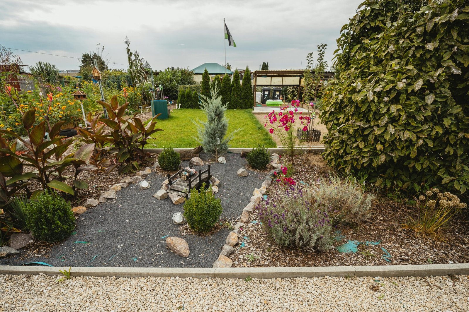 Explore a vibrant community garden featuring lush greenery, colorful flowers, and a quaint stone pathway.